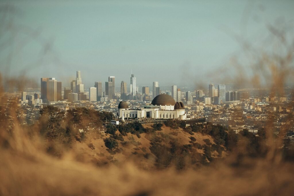 The Griffith Observatory with Los Angeles skyline backdrop at sunset, showcasing urban architecture.